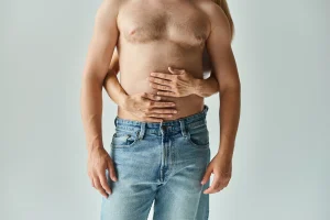 Hombre con el torso descubierto y mujer que le abraza.
