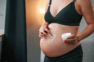 Mujer embarazada dándose crema.