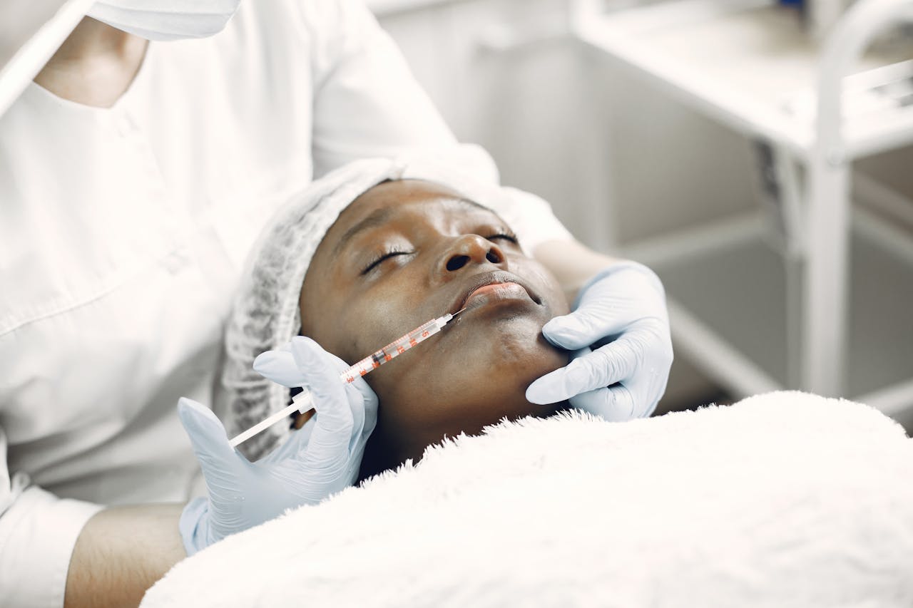 Paciente recibiendo inyección estética en el rostro con relleno dérmico, aplicado por profesional con guantes azules en clínica.